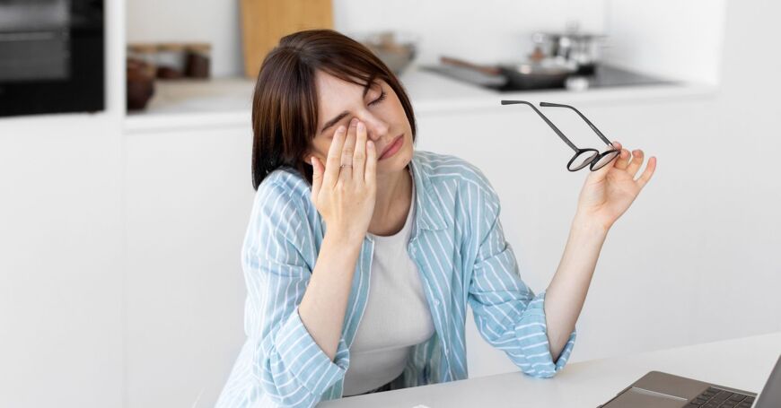 Päätetyötä tekevä nainen hieroo kuivia silmiä.