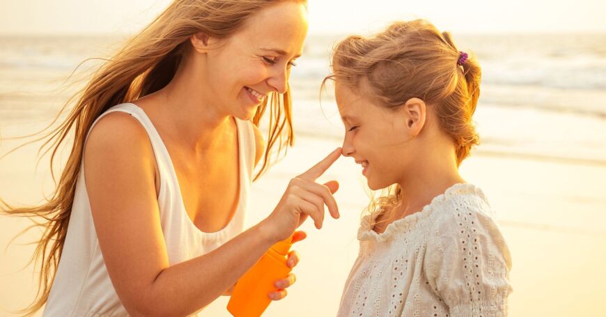 Nainen levittää lapsen iholle lasten aurinkorasvaa.