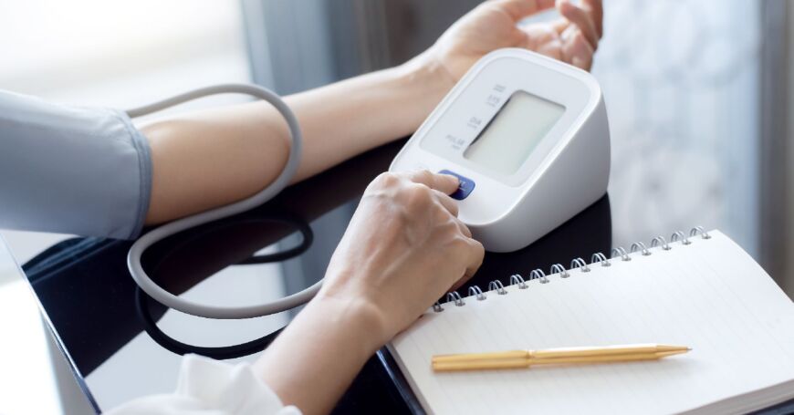 Nainen mittaa verenpainetta verenpainemittarilla vasemmasta olkavarresta