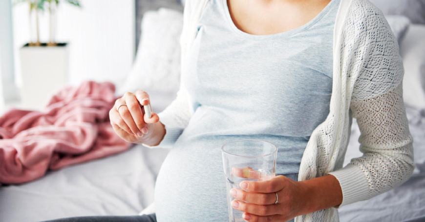raskaana oleva nainen ottaa lääkkeitä veden kanssa